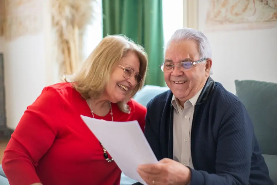 Casal de idosos lendo um documento juntos e sorrindo