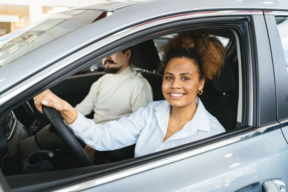 Mulher sorrindo ao volante de um carro